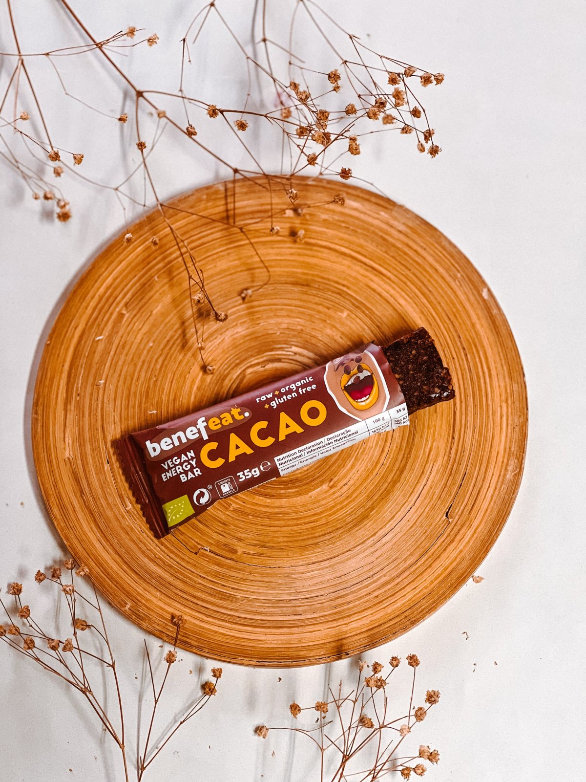 Open Cacao bar on a wooden plate with dried flowers