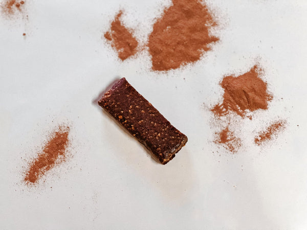 Unwrapped Cacao bar surrounded by cacao powder