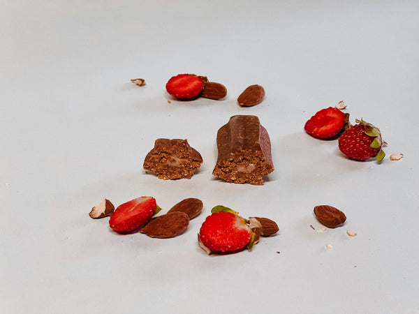 Strawberry Almond churro broken in half among strawberries and almonds