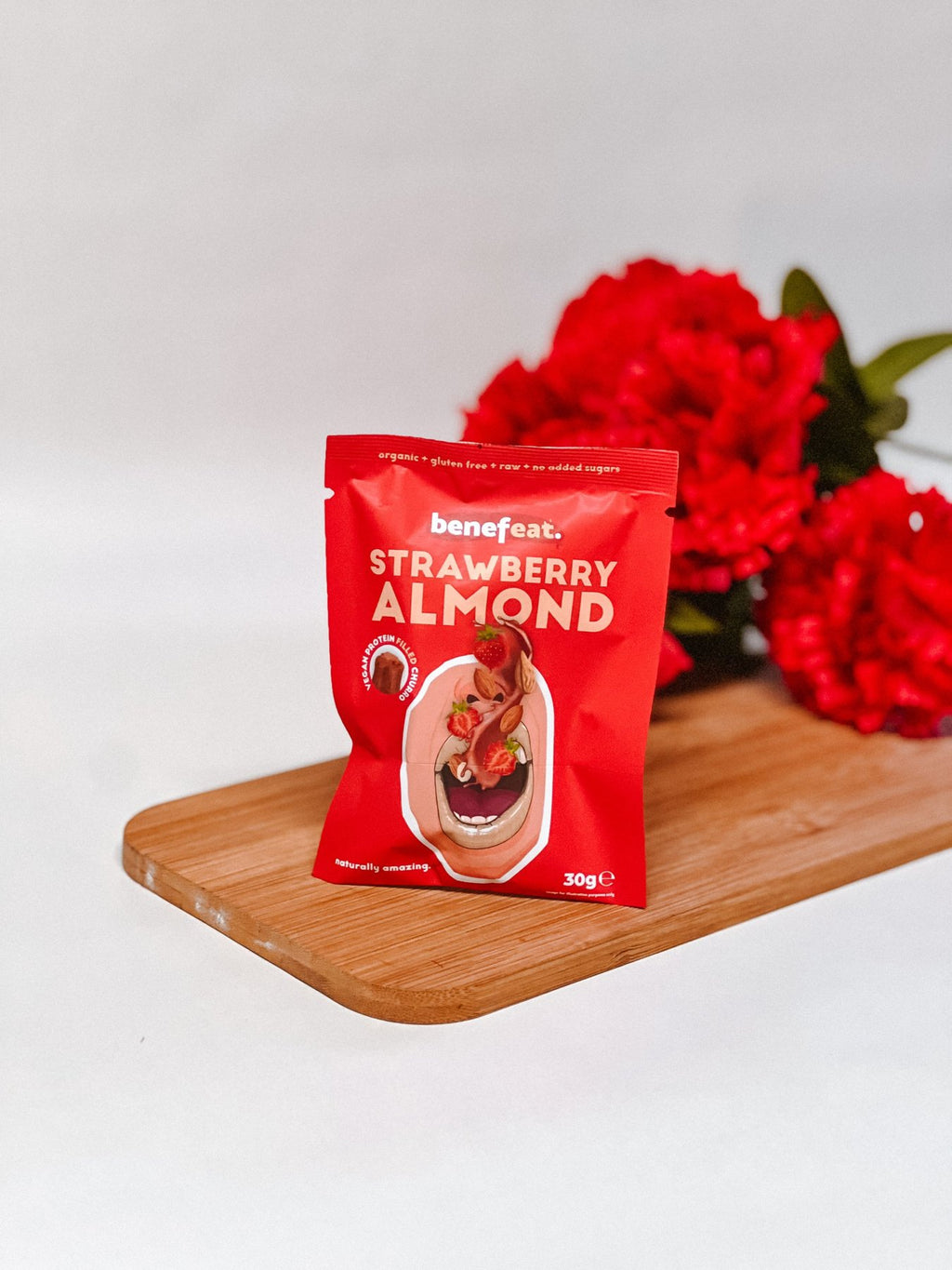 Strawberry Almond pack on a wooden board with red flowers