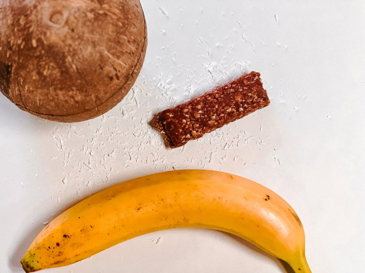 Unwrapped Coconut Banana bar between a coconut and a banana