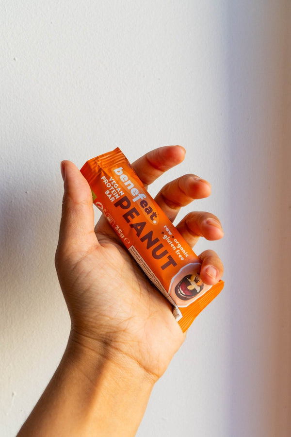 Hand holding a Peanut bar against a white wall