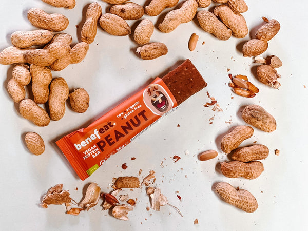Open Peanut bar pack surrounded by peanuts in their shells